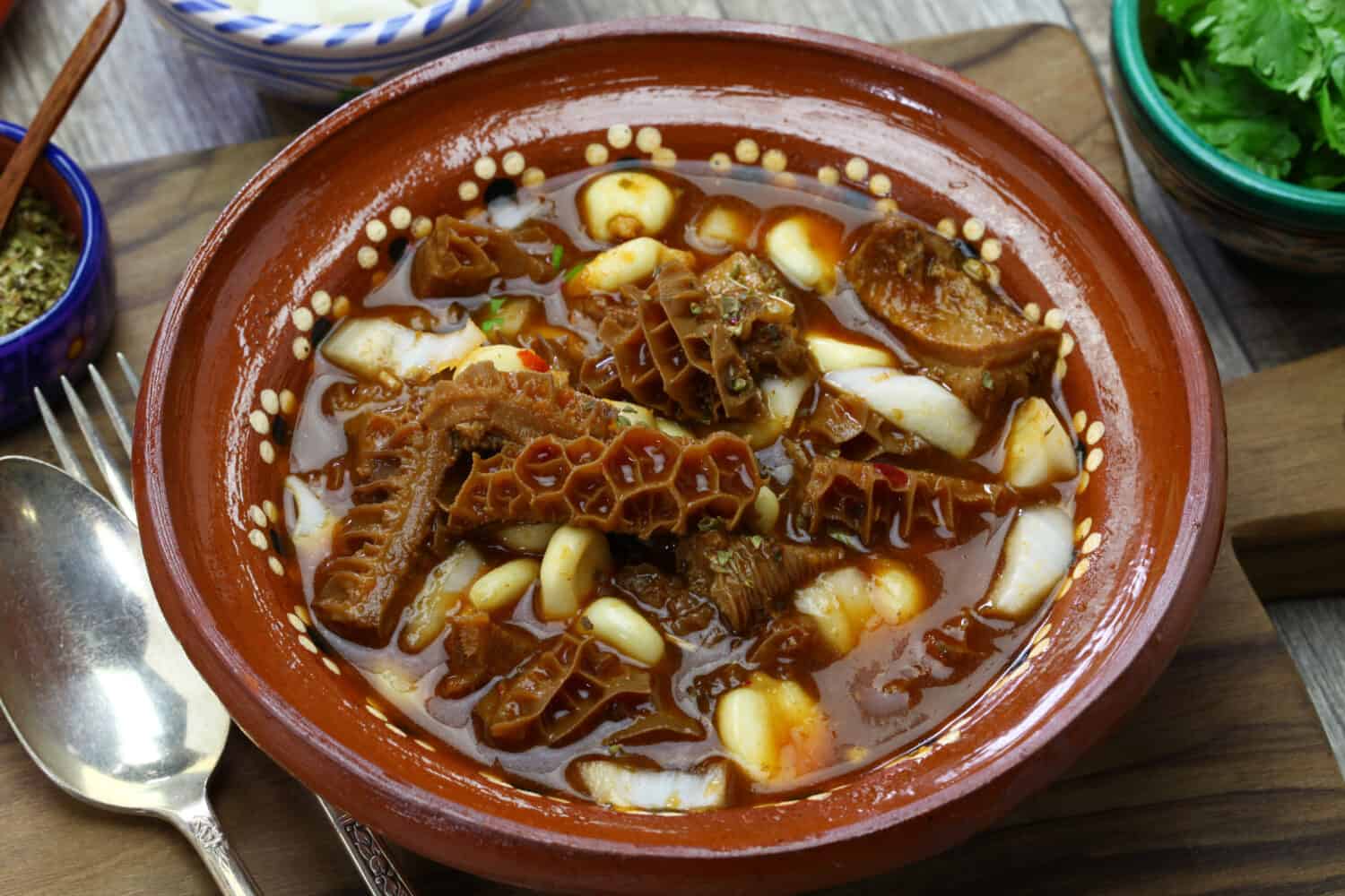 Menudo Rojo is a traditional mexican soup made with tripe and hominy in broth with chile guajillo base.
