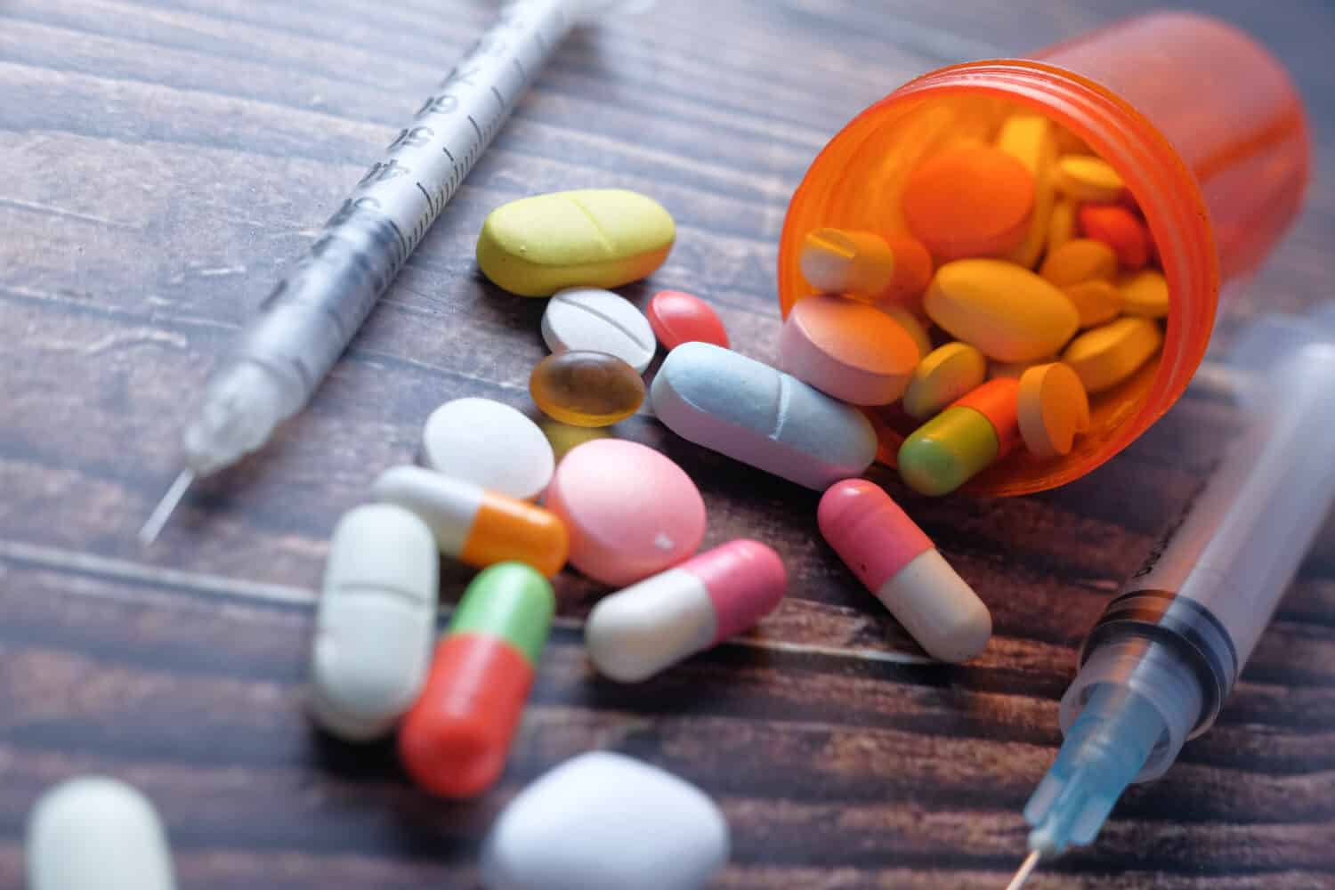 the concept of drug overdose, syringe and pills on dark background, close up