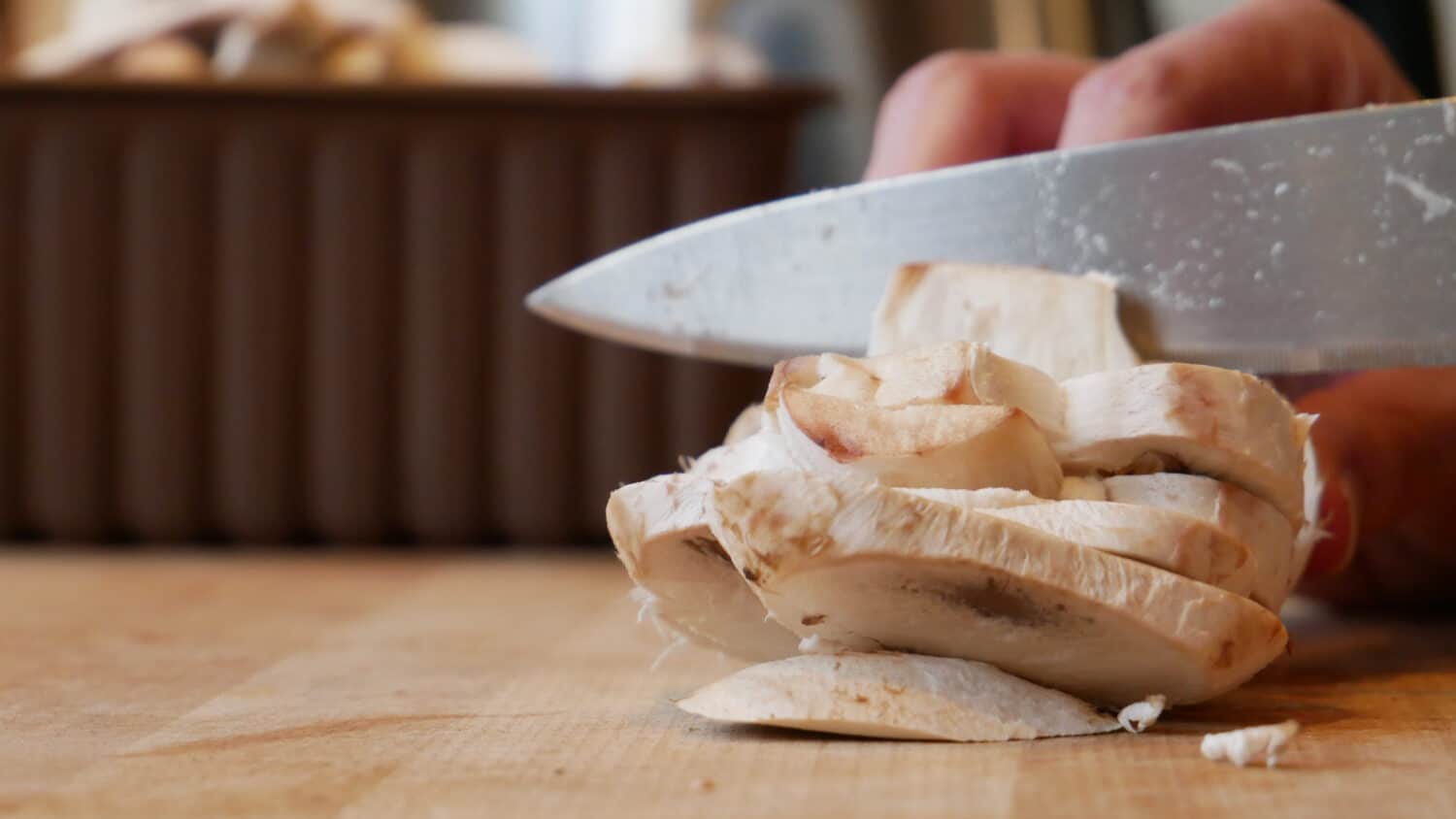 Chopping and slicing mushrooms with a sharp chef's knife on a wooden cutting board