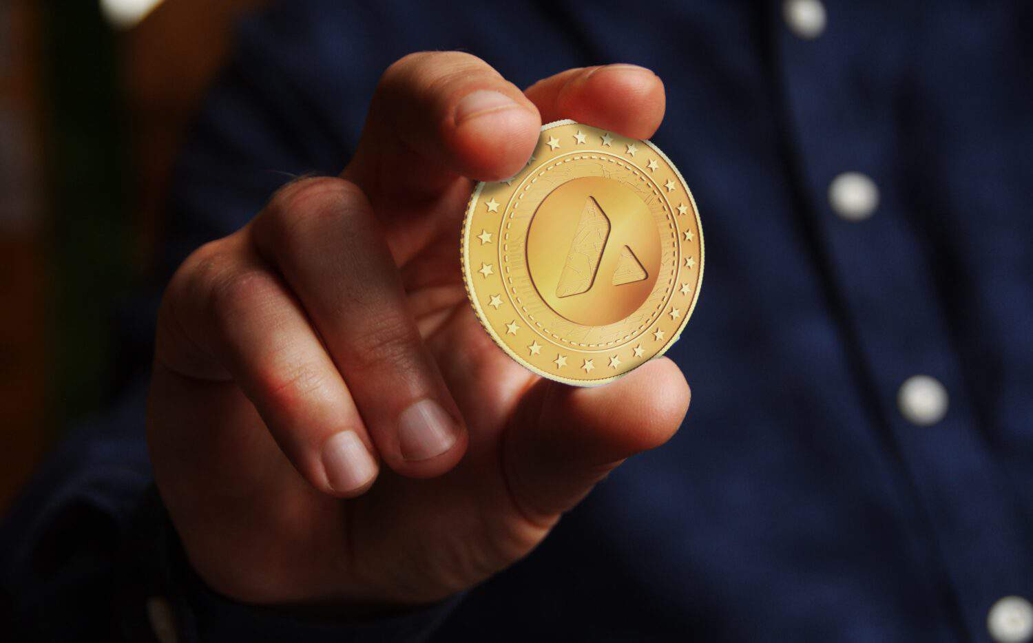 Avalanche AVAX cryptocurrency symbol golden coin in hand abstract concept.