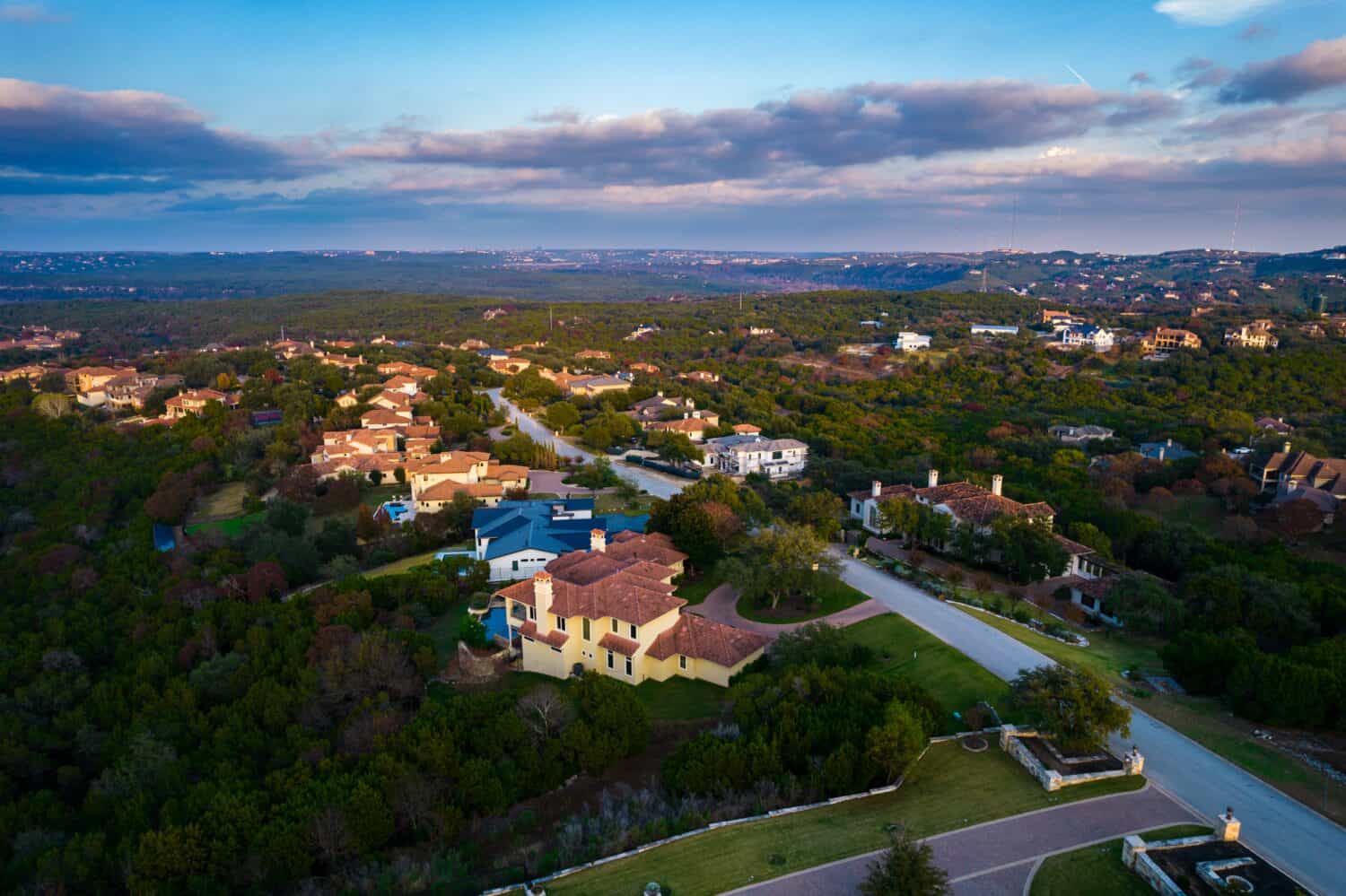 huge mansion homes aboe barton creek west hills of Austin Texas Sunset above rooftops and houses in million dollar Suburb
