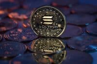 Solana SOL Cryptocurrency Physical Coin placed on crypto altcoins and lit with orange and blue lights in the dark Backgrond. Macro shot. Selective focus.