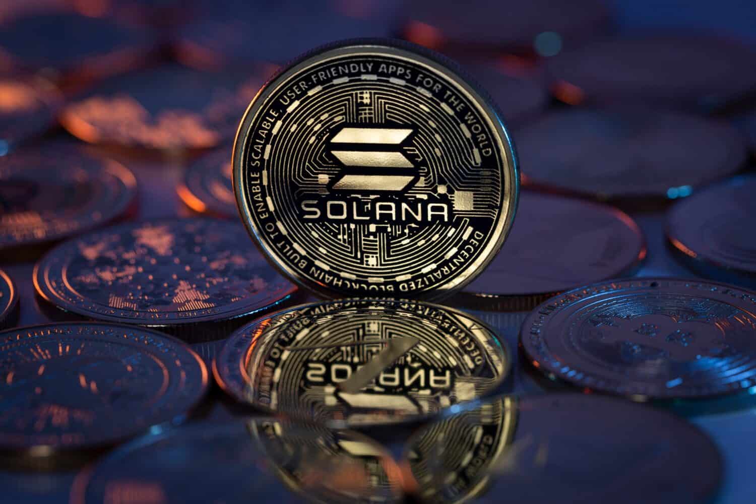 Solana SOL Cryptocurrency Physical Coin placed on crypto altcoins and lit with orange and blue lights in the dark Backgrond. Macro shot. Selective focus.
