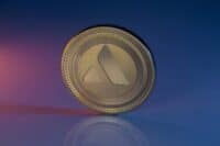 Avalanche AVAX Cryptocurrency Physical Coin Placed on reflective surface and lit with orange and blue lights.