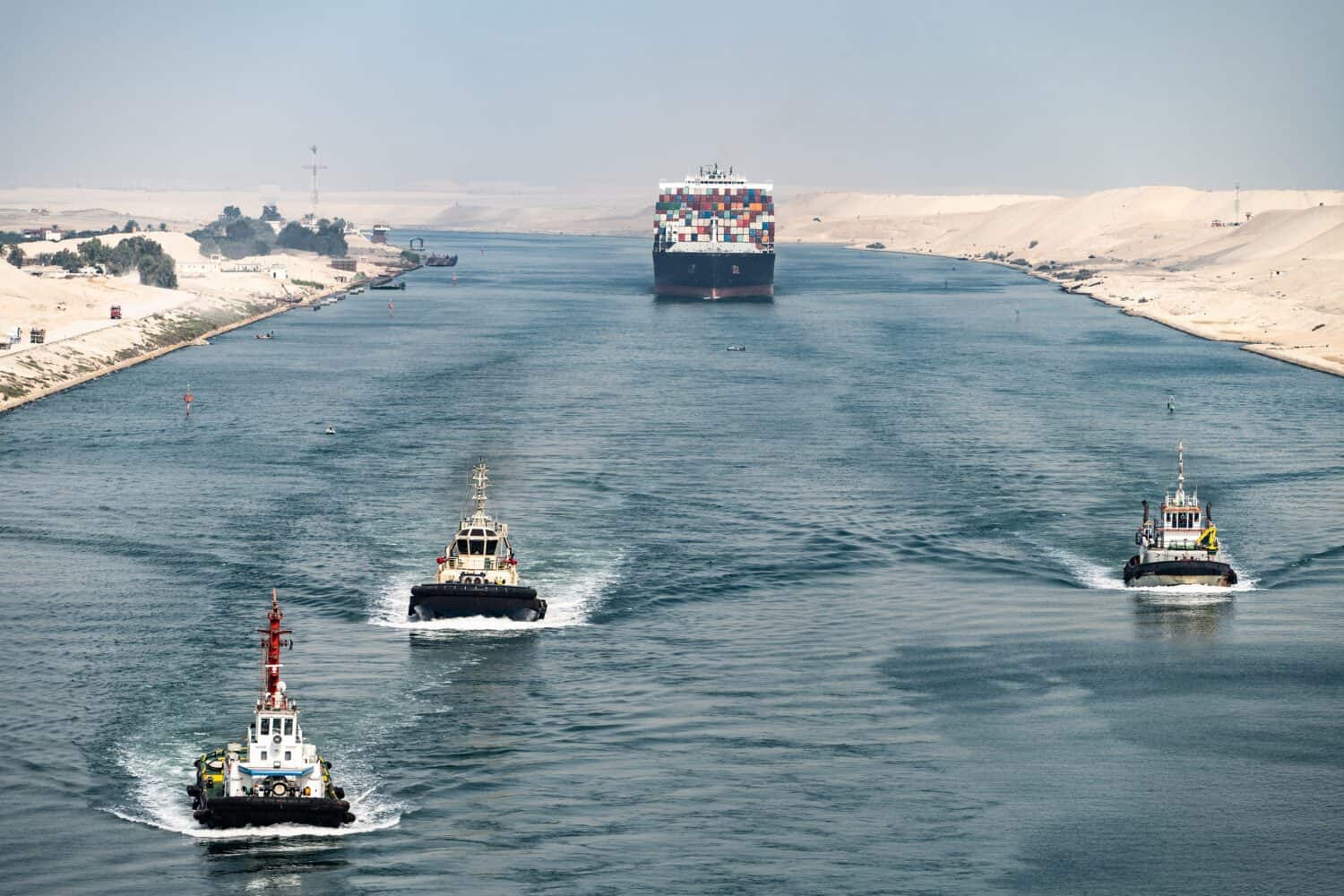Huge cargo ships with pilot boats navigate by Suez Canal, Egypt. Concept of transportation and logistics