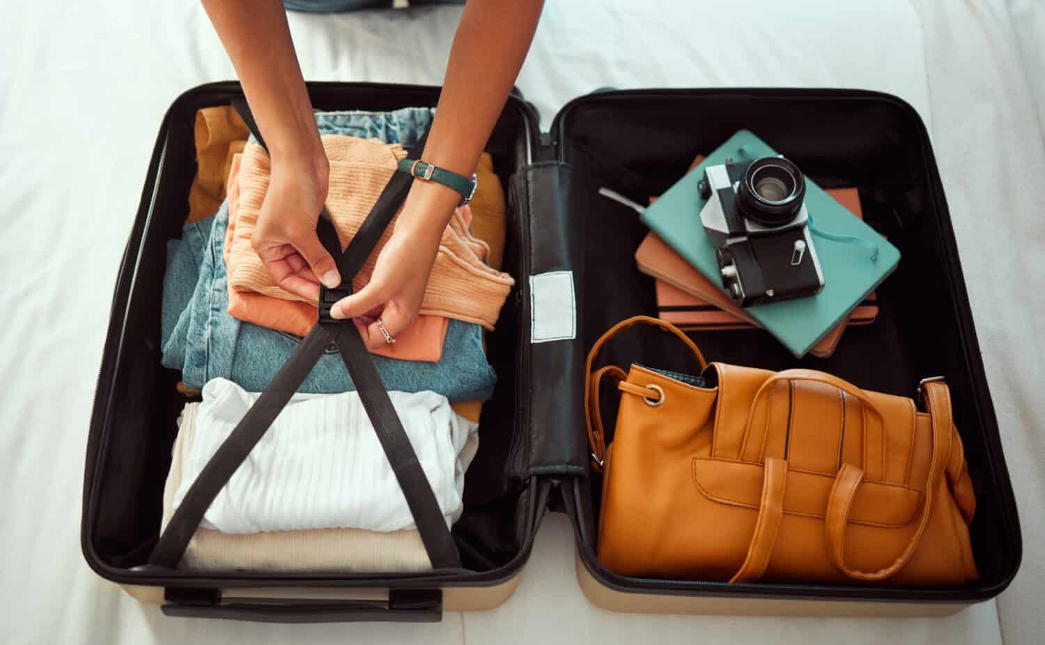 Travel suitcase, bedroom and hands of woman packing for Europe holiday, vacation or adventure tourist journey. Hospitality, hotel bed and photographer with luggage bag, clothes and camera in Madrid