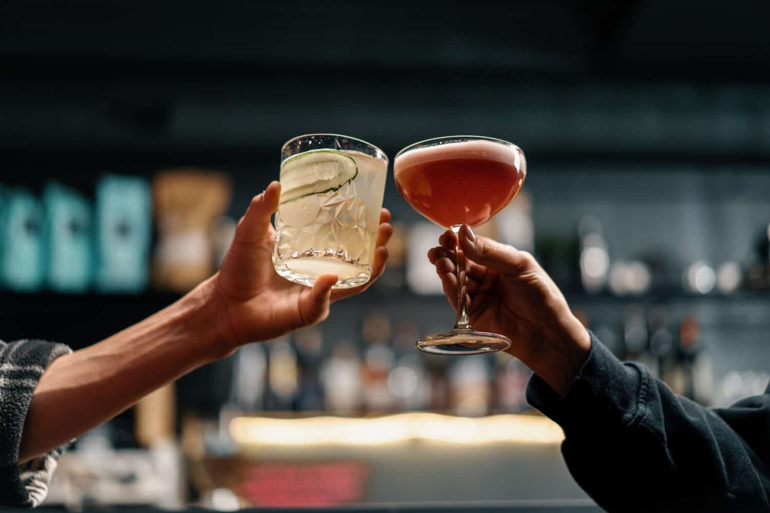 Close up of two people cheering cocktails in bar or disco club drinks and cocktails concept
