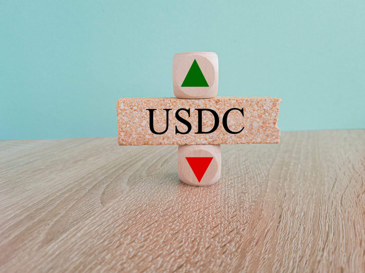USDC price symbol. A brick block with arrow symbolizing that USD coin index price are going down or up. Beautiful wooden table blue background. Business and gold price concept. Copy space.
