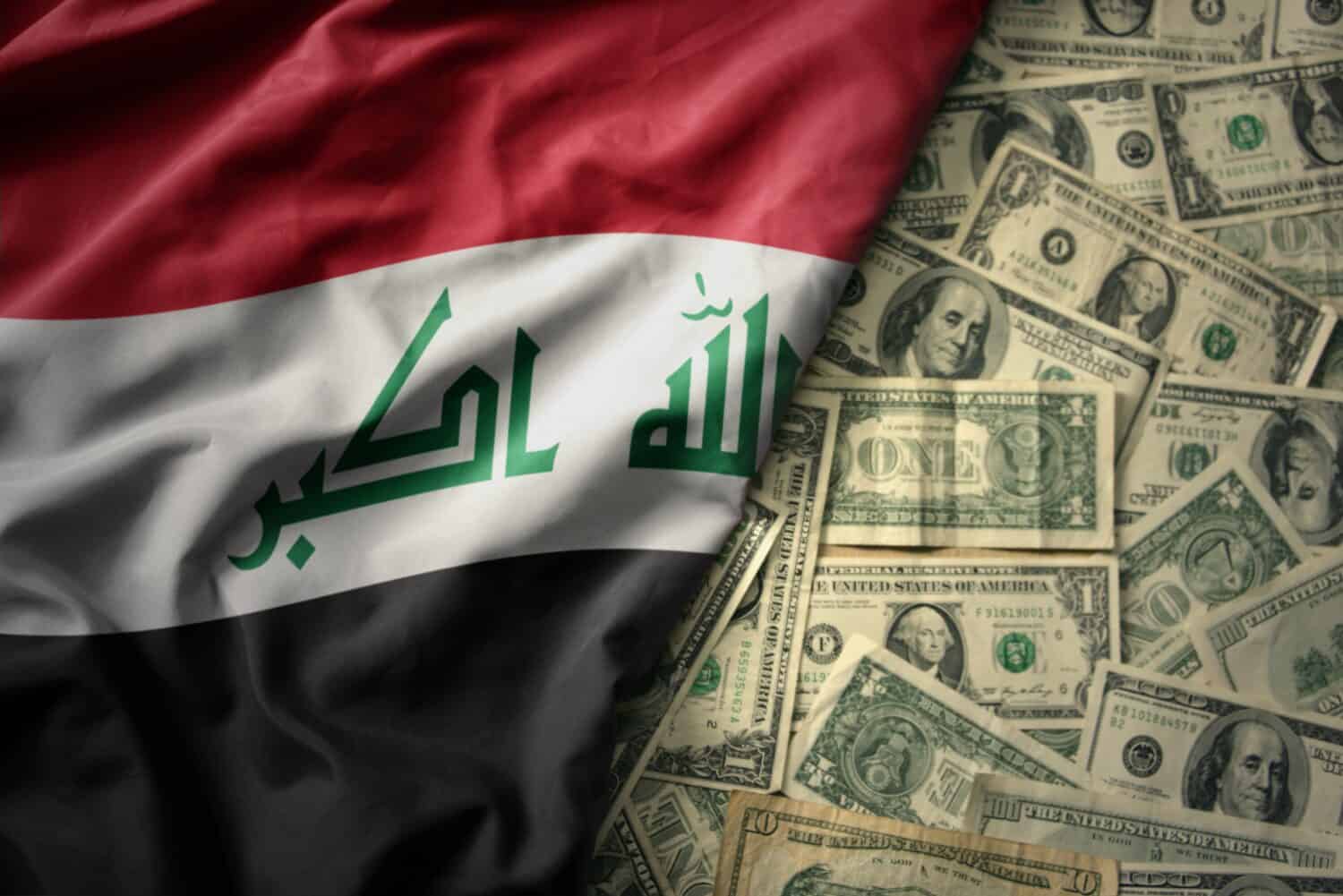 big colorful waving national flag of iraq on a american dollar money background. finance concept