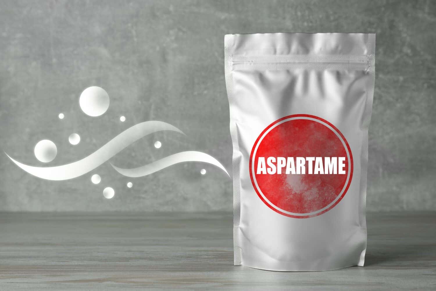 Aspartame. Foil package with artificial sweetener on gray wooden table