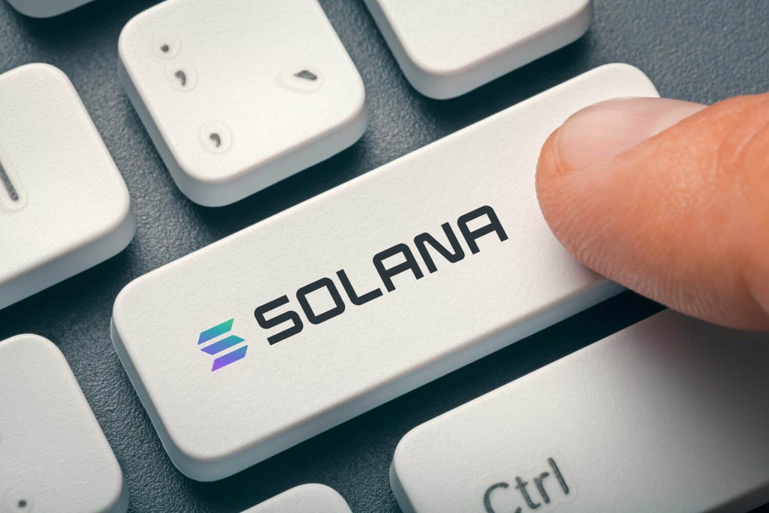 Cryptocurrency trading or exchange concept: Male hand index finger pressing computer key with Solana token logo.