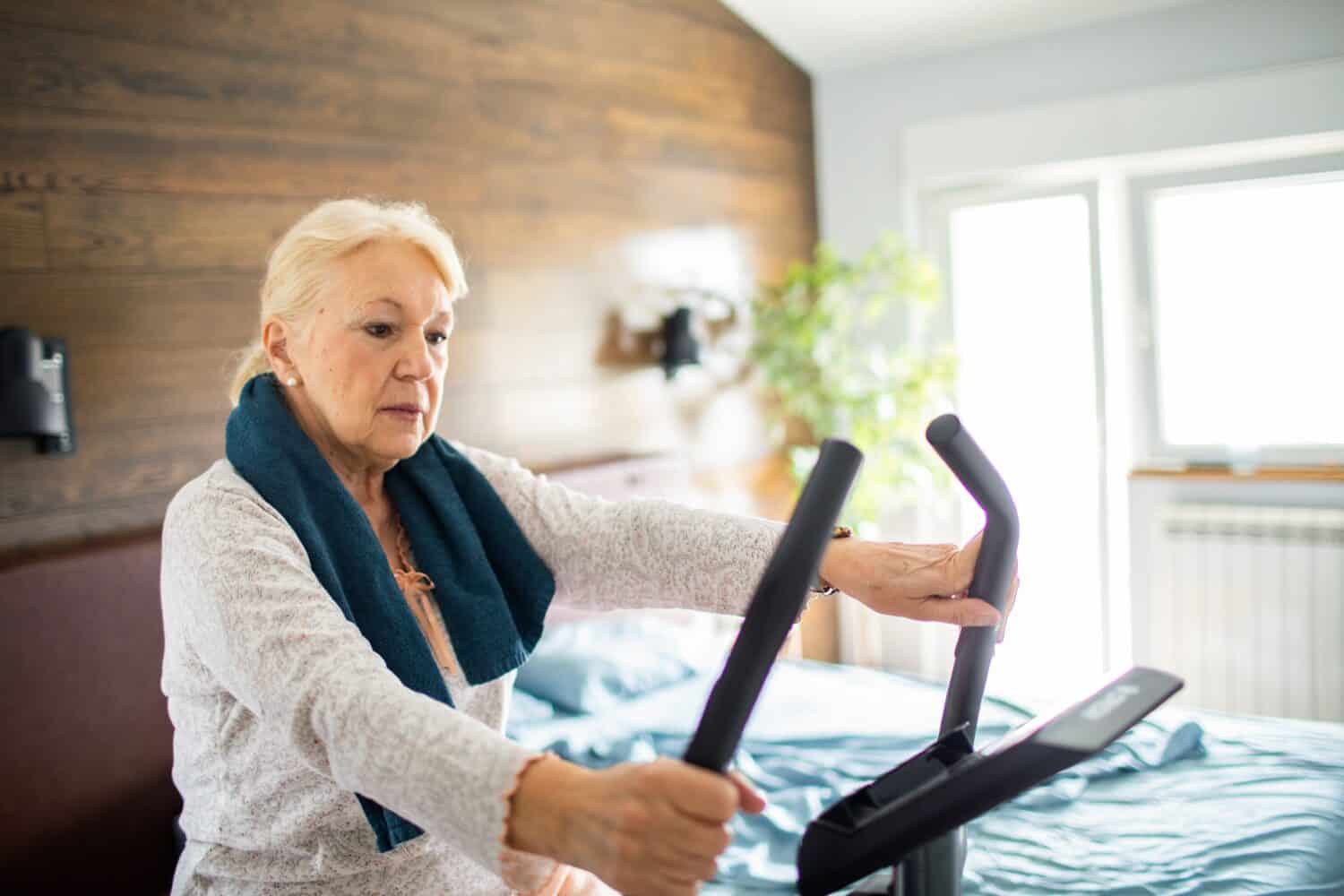 Senior woman working out on fitness bike at home