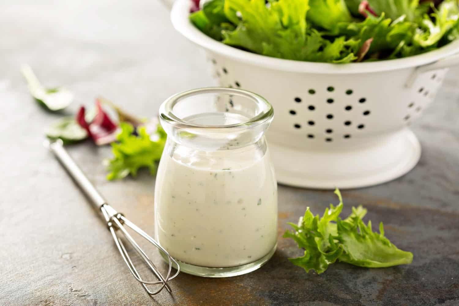 Homemade ranch dressing in a small jar with fresh greens.