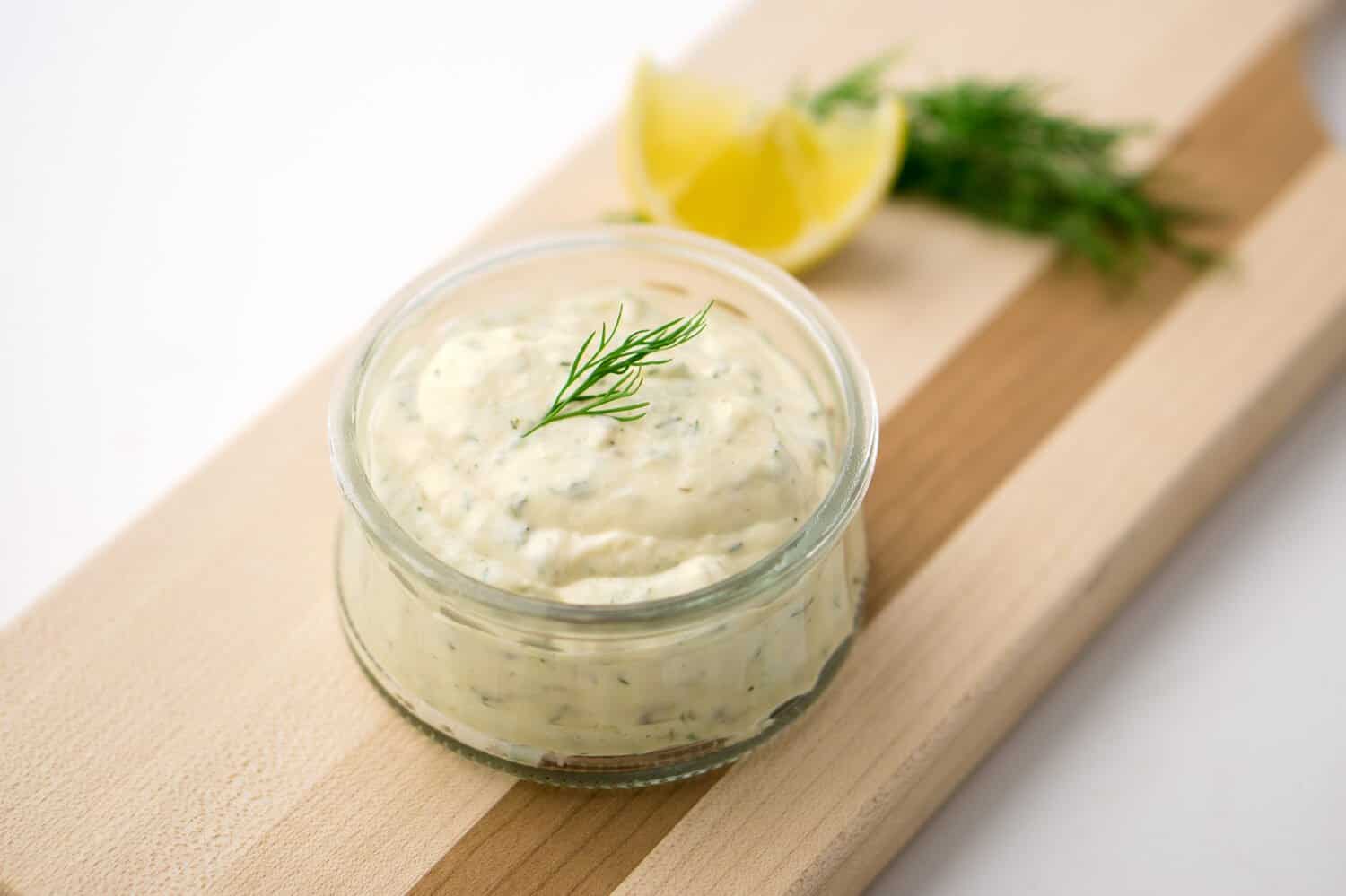Homemade tartar sauce on white background. Made of fresh mayonnaise, lemon and various herbs. This classic creamy sauce is delicious with deep fried fish, seafood and many other dishes.