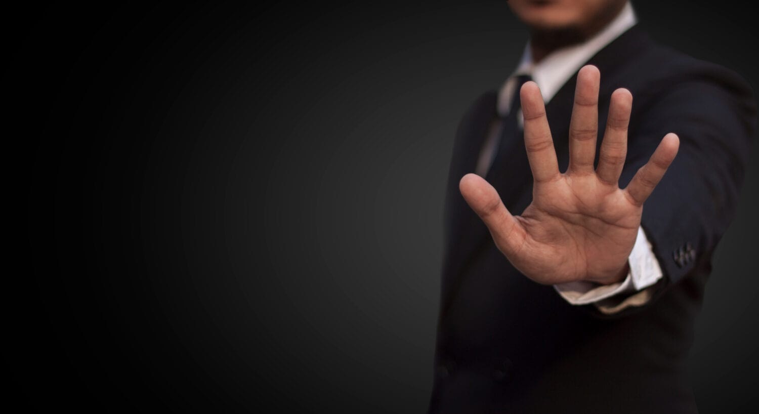 Business Man show stop gesture with his hand on dark background.picture have space for put your text.