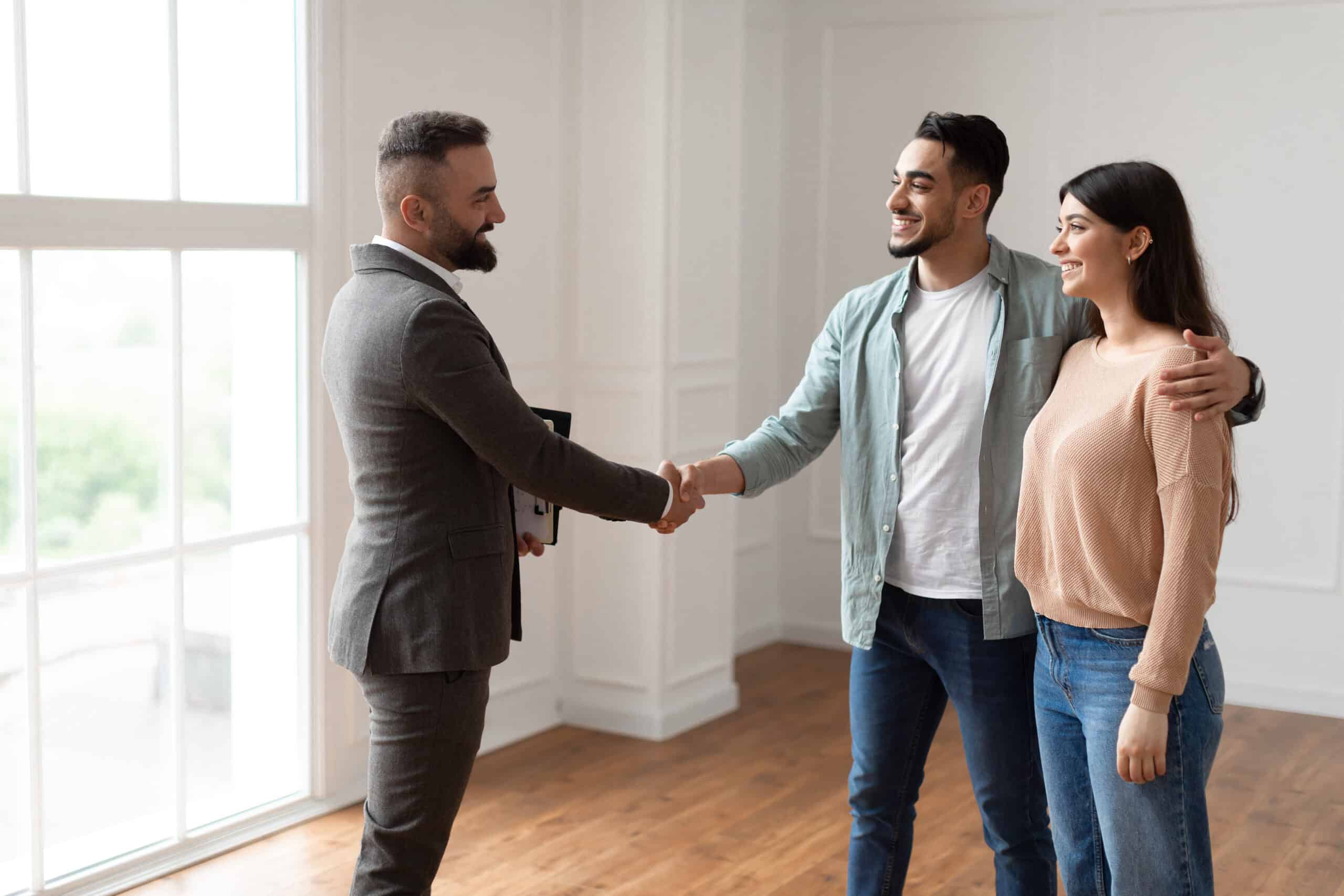 Millennial Couple Buying New Apartment, Shaking Hands With Real Estate Agent