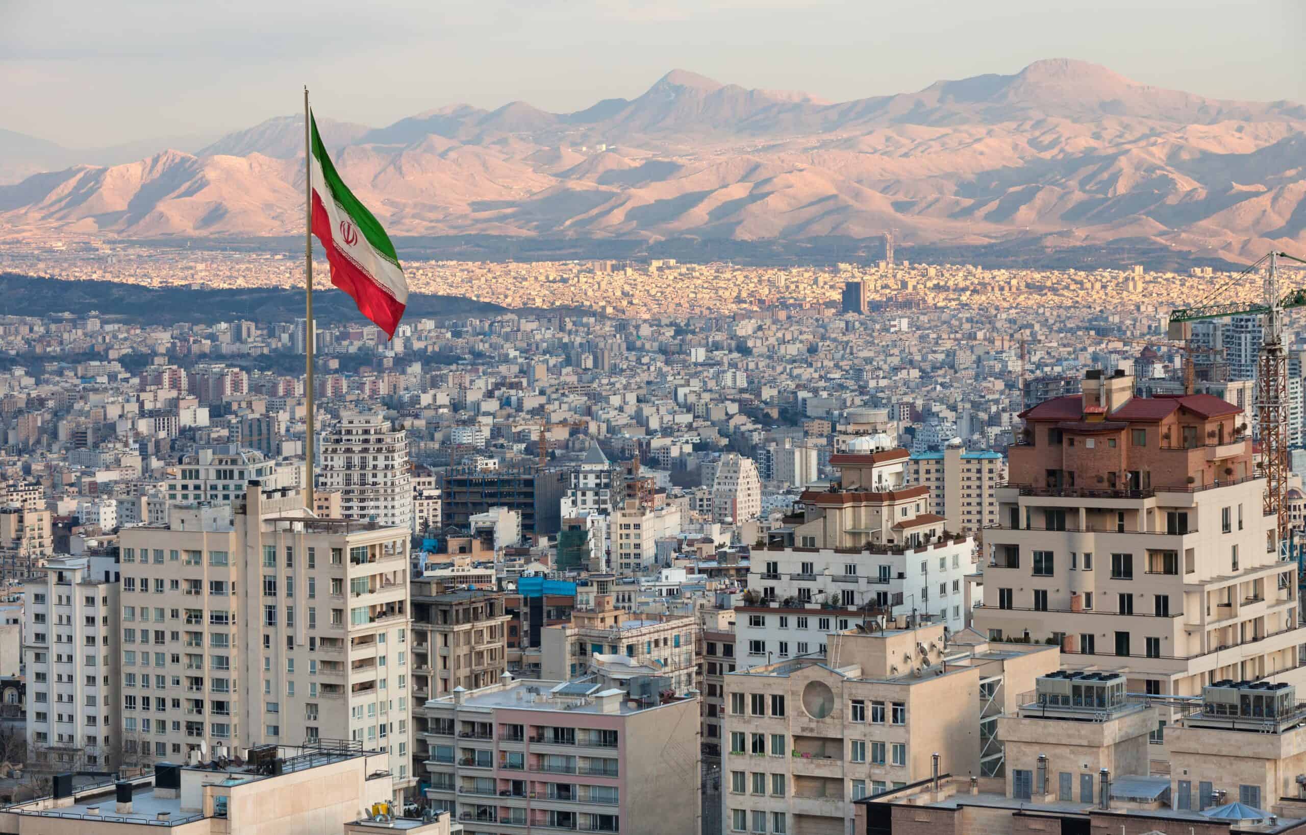 Iran | Aerial view of Tehran Skyline at Sunset with Large Iran Flag Waving in the Wind