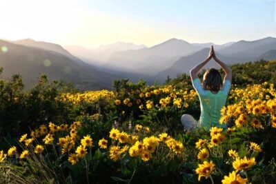 Seattle WA people | Woman in yoga pose meditating in meadows among Sunflowers.
