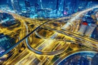 Aerial view of big highway interchange with traffic in Dubai, UAE, at night. Scenic cityscape. Colorful transportation, communications and driving background.
