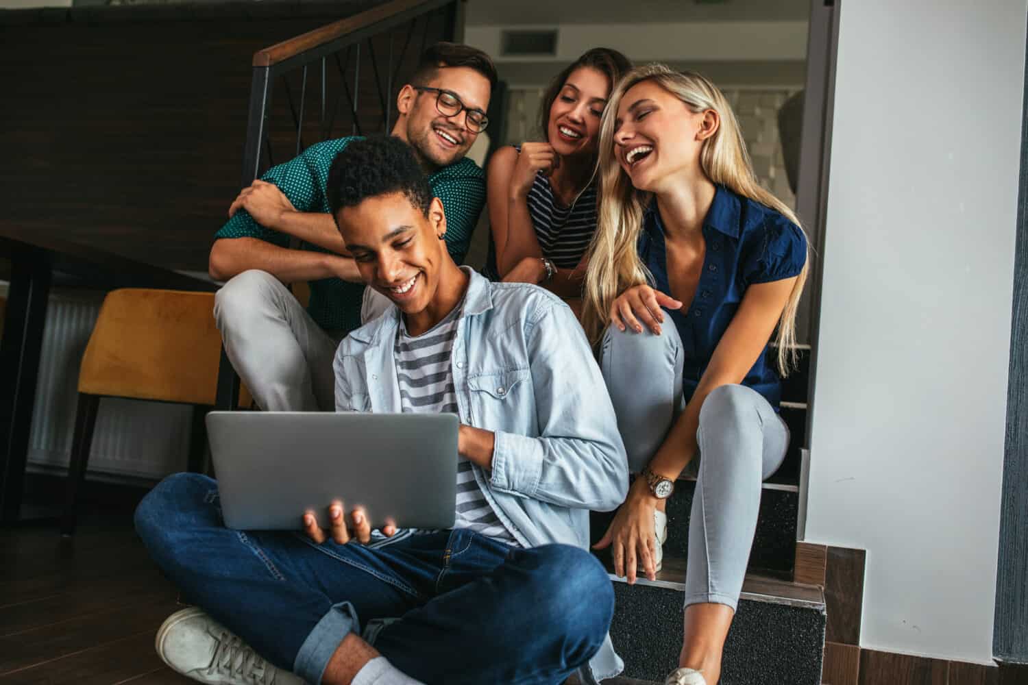 Group of friends sitting and watching something on a laptop computer