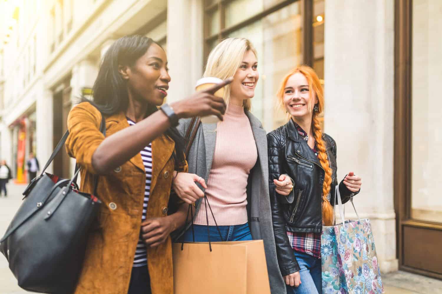 Multiracial group of women shopping and walking in London. Three girls, mixed race group, having fun in the city while shopping. Best friends sharing happy moments together