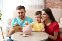 Happy family with piggy bank and money at home