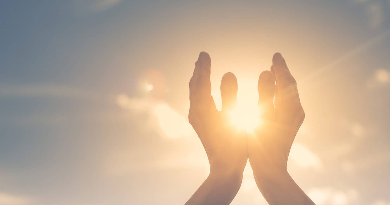 Woman hands holding the sun at dawn. Freedom and spirituality concept.