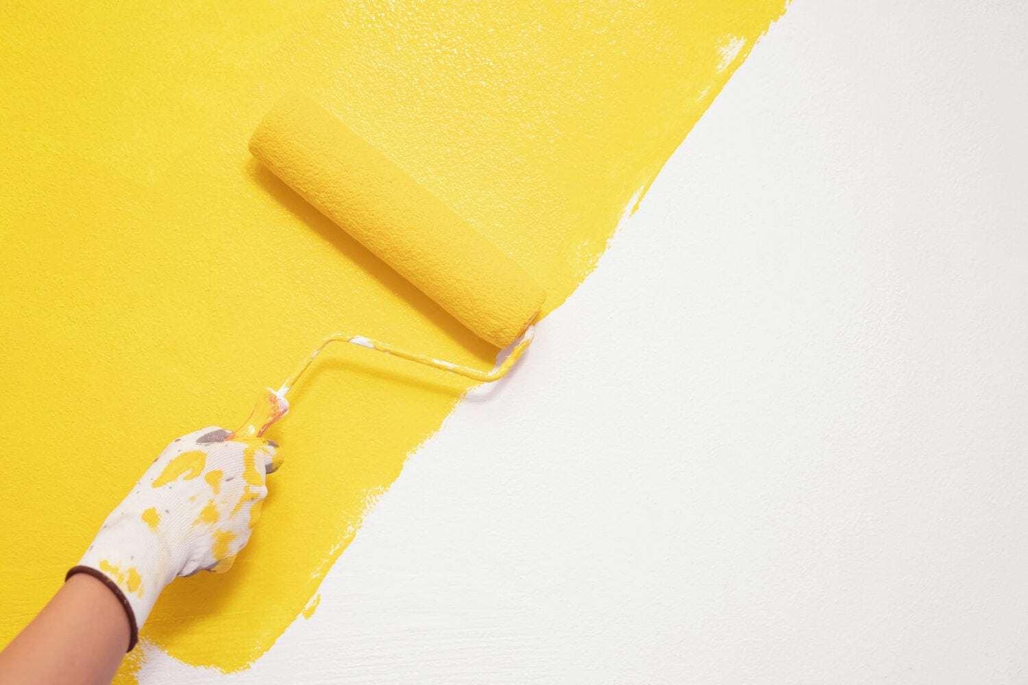 Roller Brush Painting, Worker painting on surface wall Painting apartment, renovating with yellow color paint. Leave empty copy space white to write descriptive text beside.