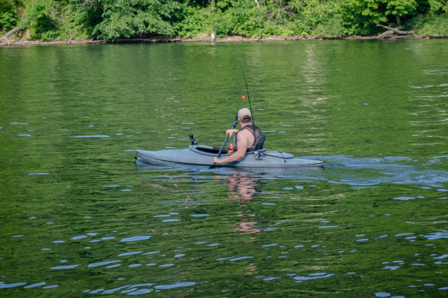 A landscape shot of a man kayaking and fishing on Cheat Lake in Morgantown, West Virginia in a fishing kayak