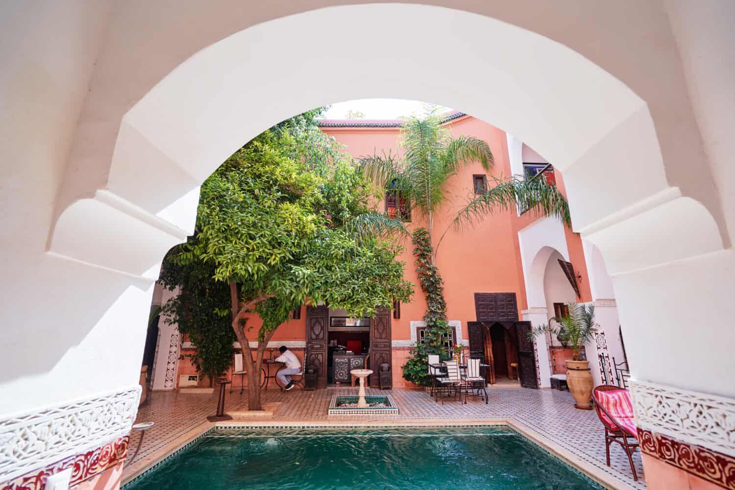 Oriental hospitality. Traveling by Morocco. Relaxing in festive moroccan traditional riad interior with swimming pool.