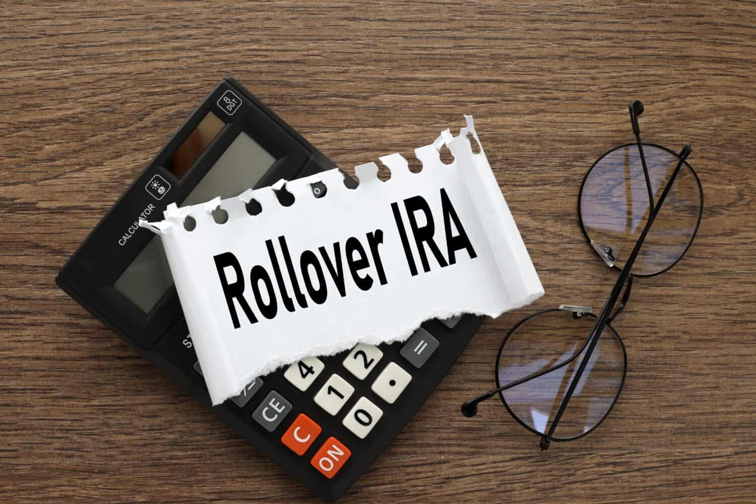 Rollover IRA. black calculator and torn paper with text