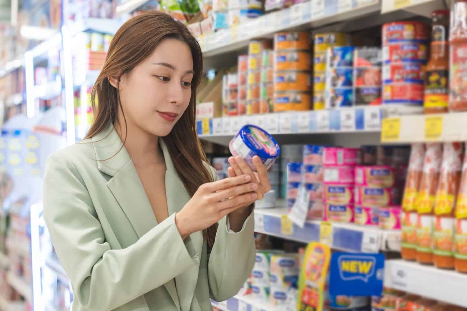 Young woman in a supermarket holding a tuna can