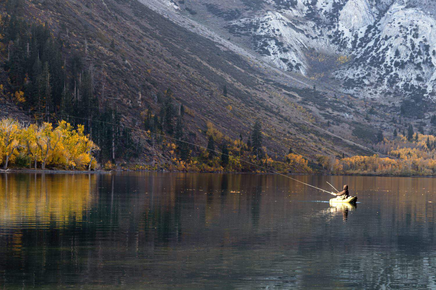 Man fishing on lake with fall foliage