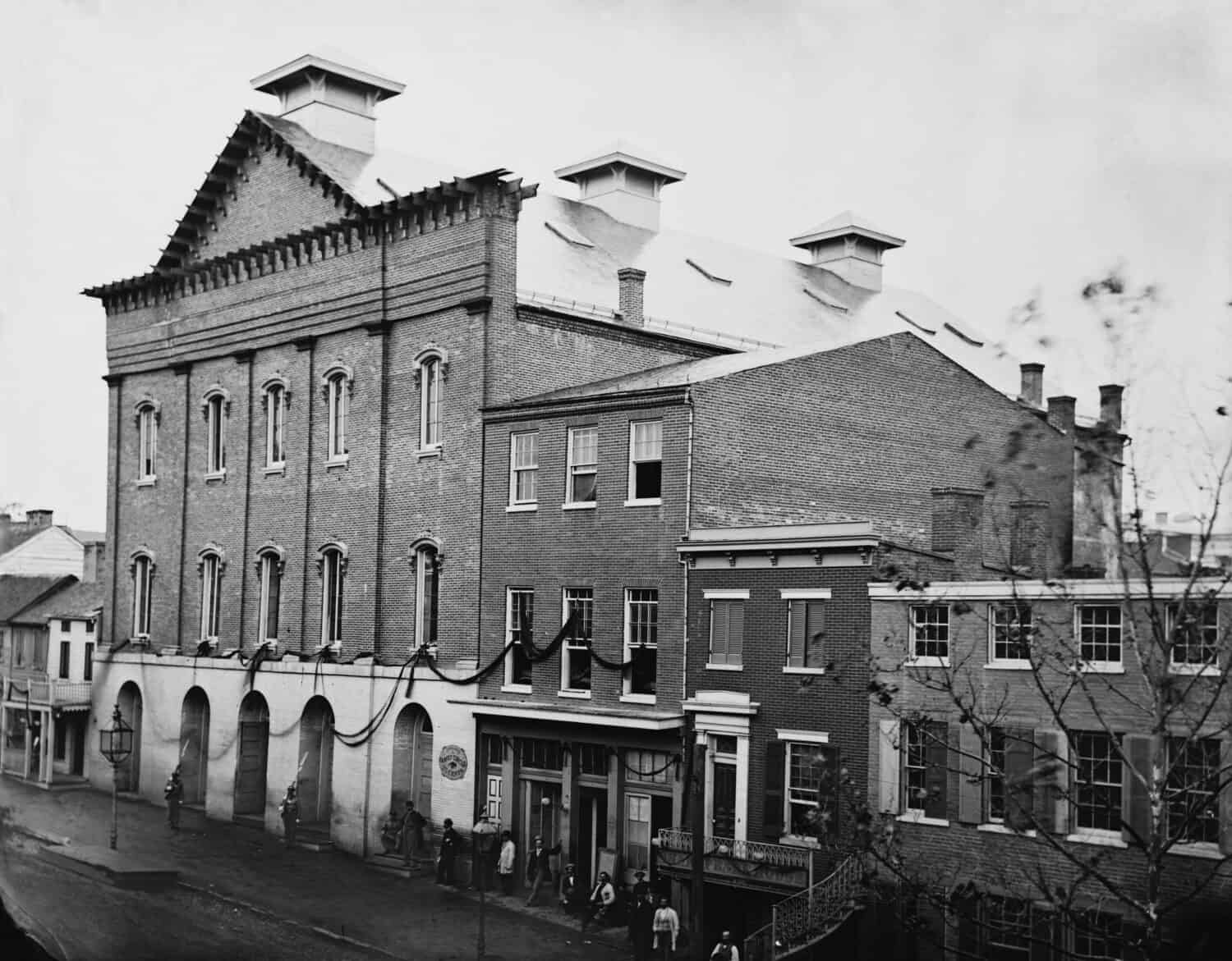 Abraham Lincoln's assassination took place in Ford's Theatre on April 14, 1865. Photo shows the post-assassination scene with guards posted at entrance and crepe draped from window.