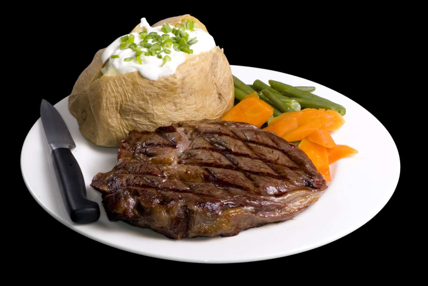 A grilled ribeye steak with baked potato and vegetables.