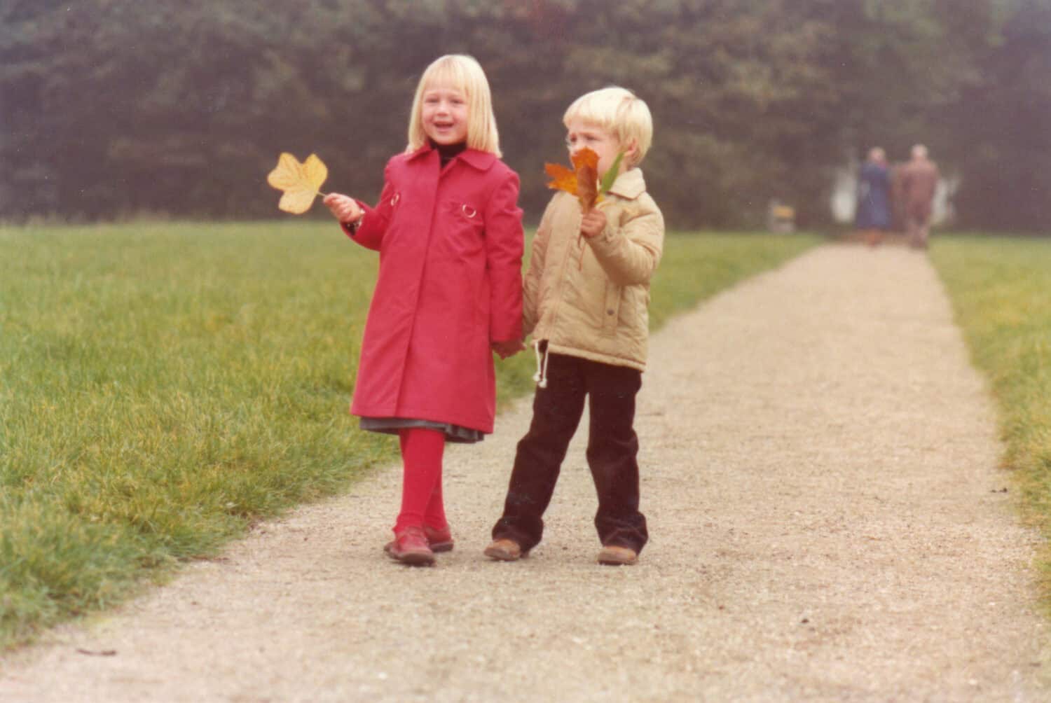 1978 vintage retro boy and girl in red coat walking in autumn park.