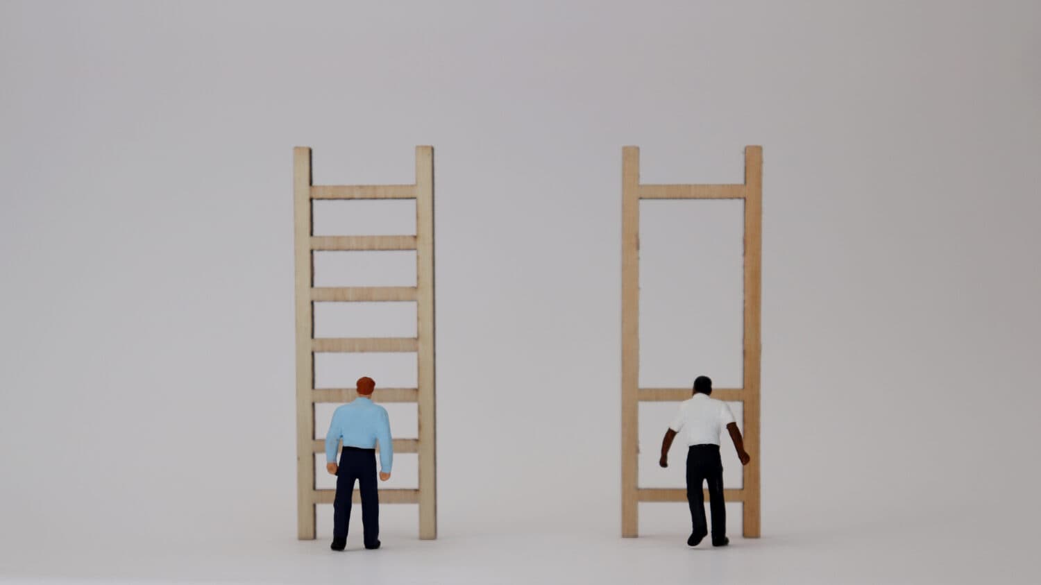 Racist concepts in employment and promotion. Miniature people and miniature wooden ladders.