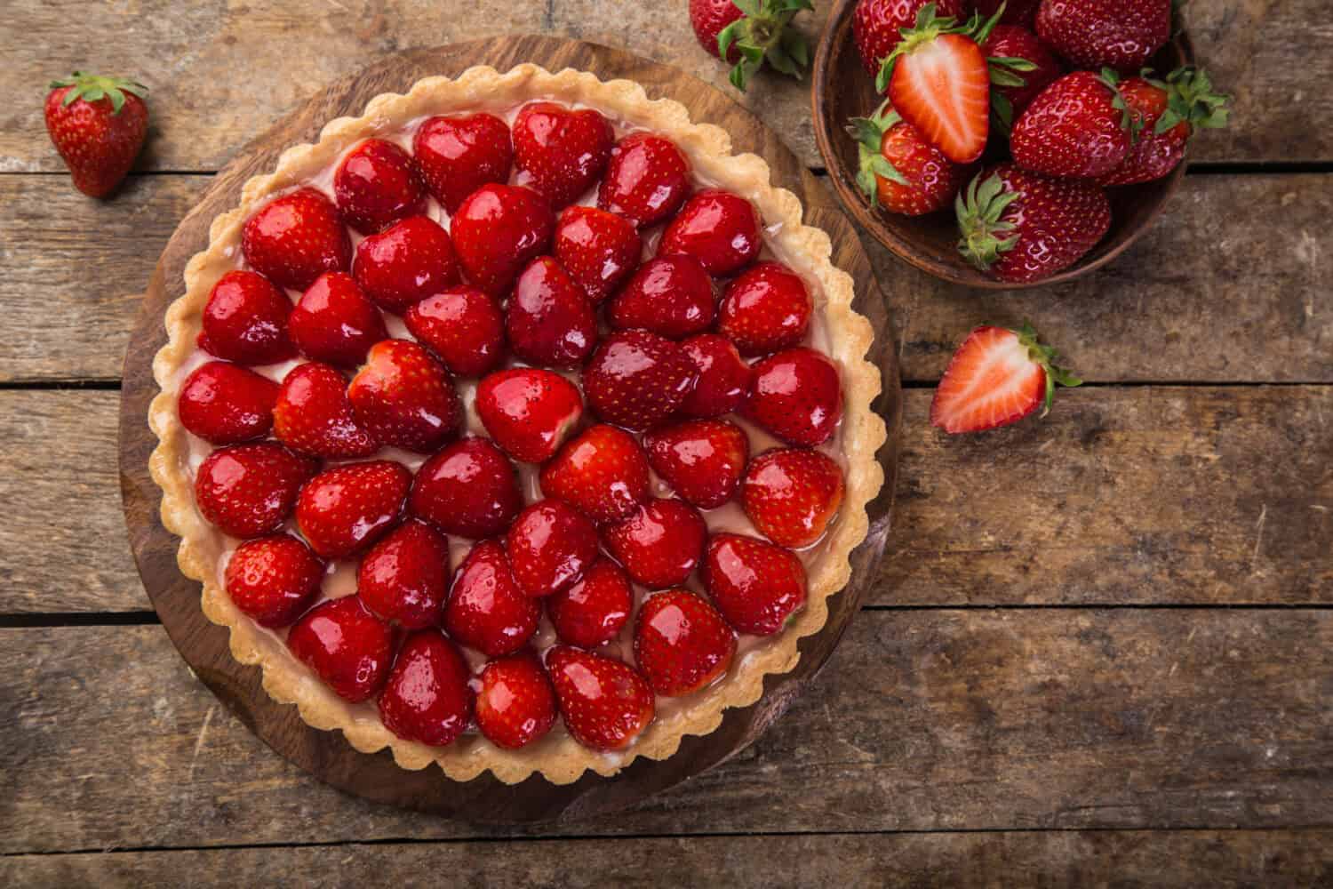 delicious strawberry tart on wooden background, top view, copy space