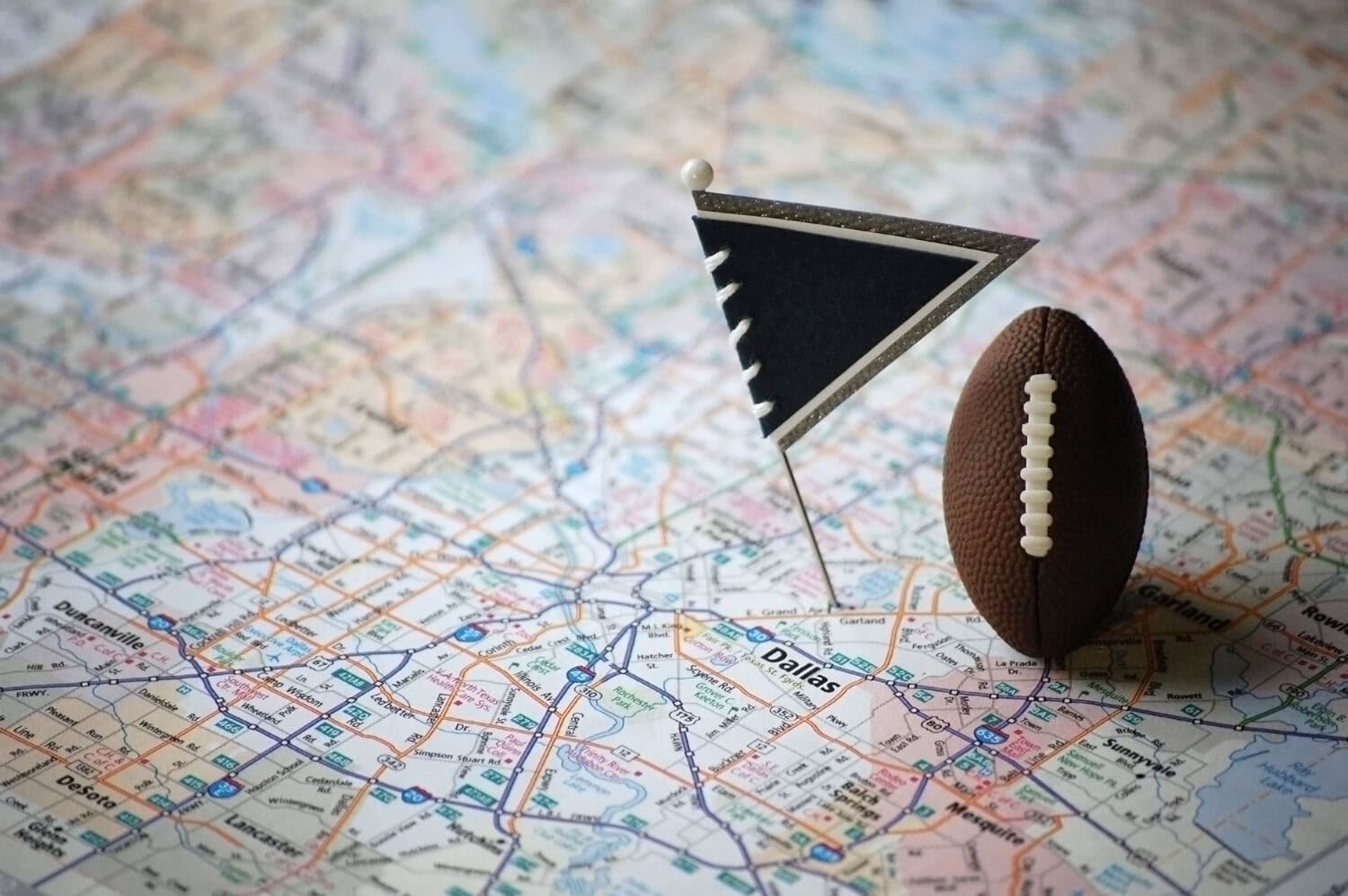 Macro shot of a flag and football placed on Dallas, Texas in a map.
