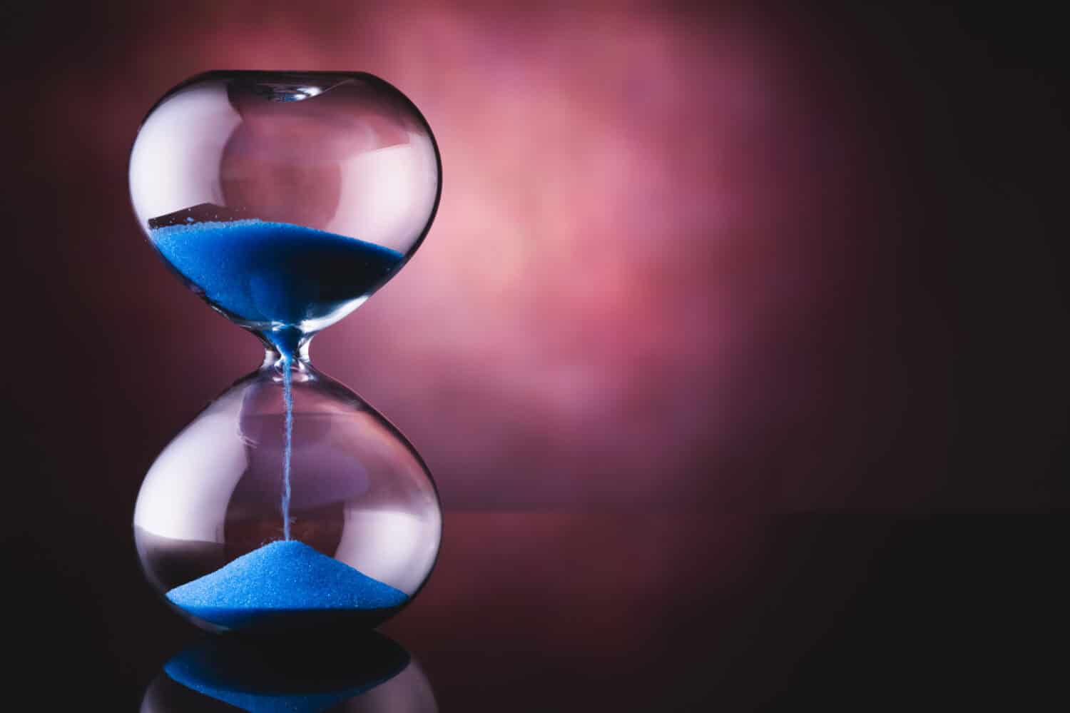 Blue sand hourglass on old background