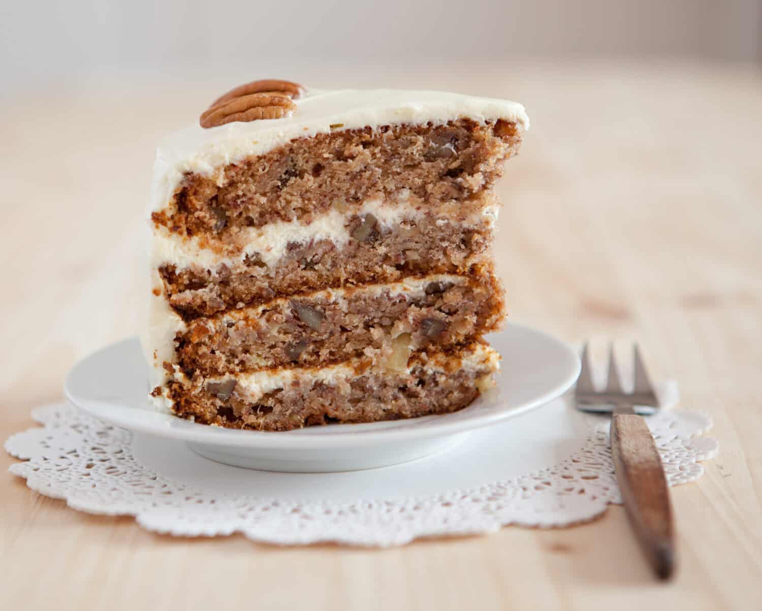 A single piece of Hummingbird cake with pecans and cream cheese frosting, selective focus