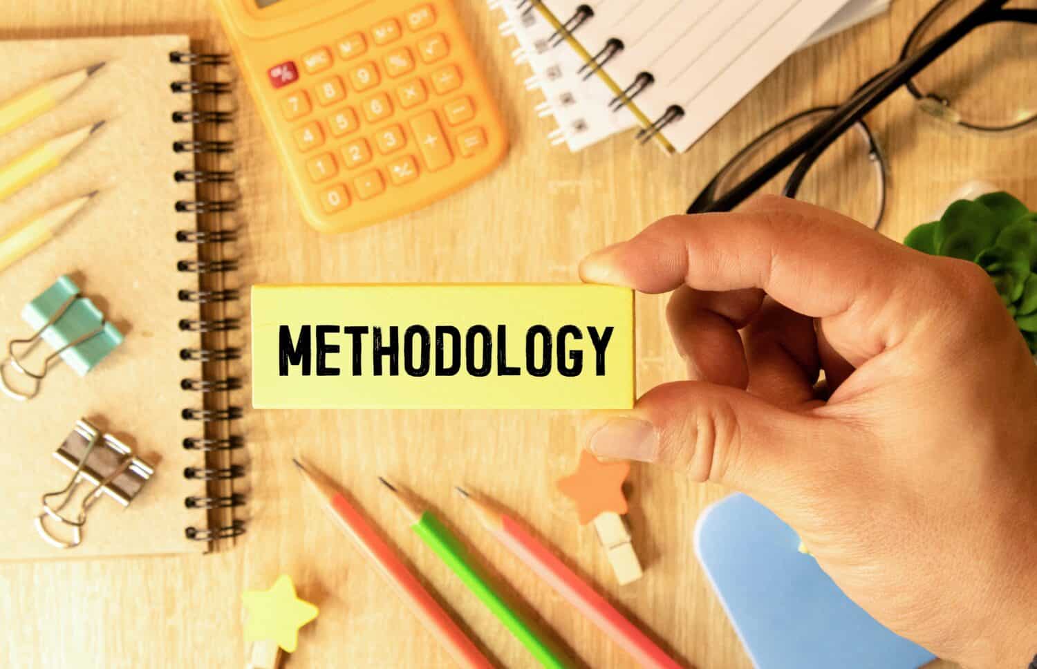 The word methodology written on a notebook on business office desktop. System of methods used in a study or activity concept.