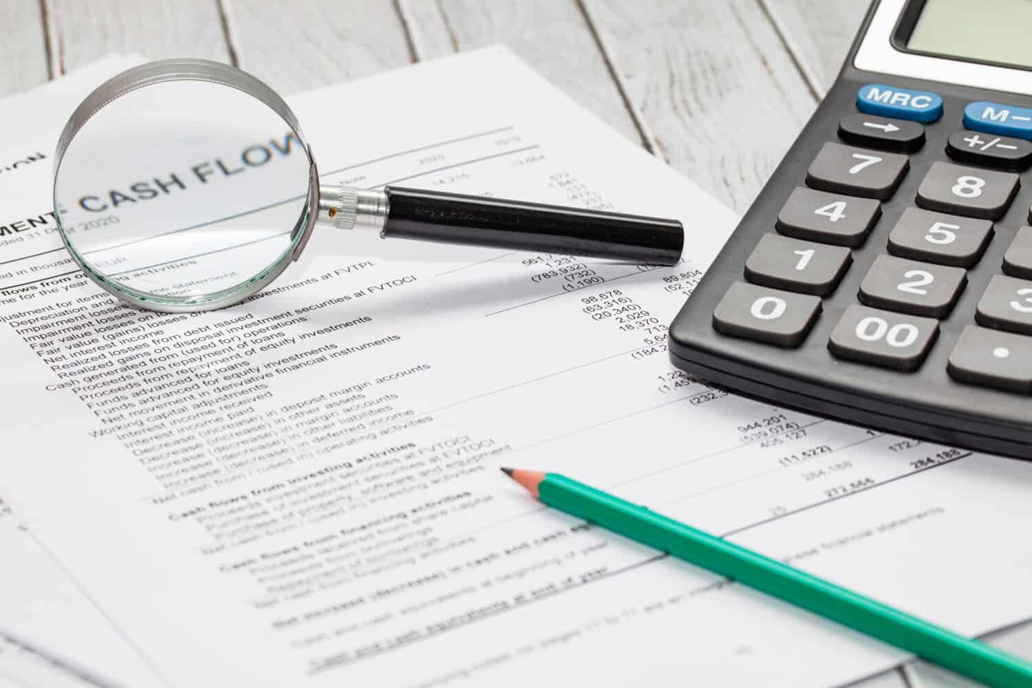 cash flow statement with calculator, pen and hand glass