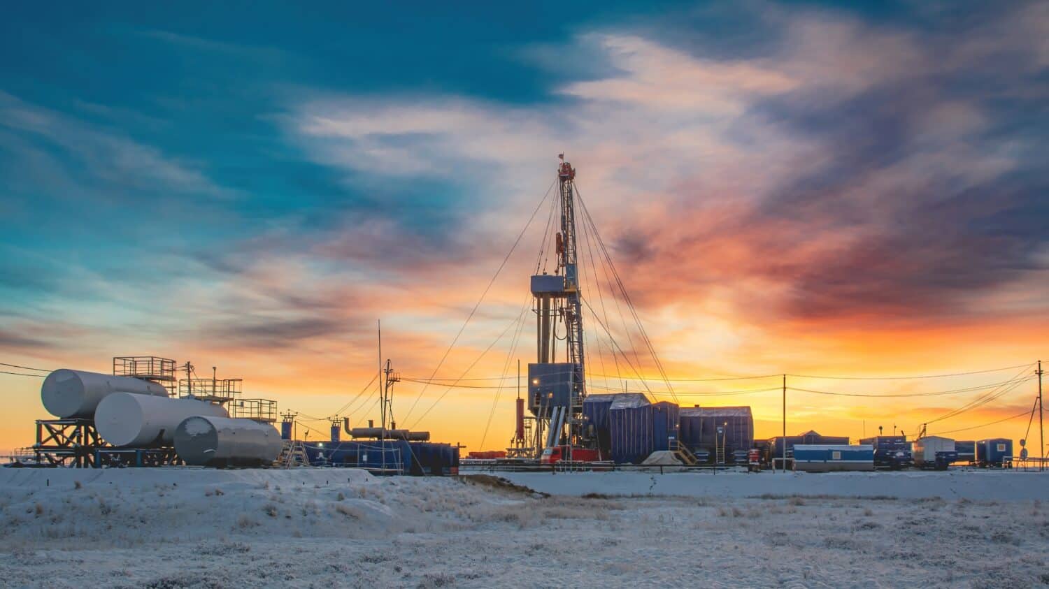 Equipment and infrastructure of the drilling rig for drilling oil and gas wells in the field of the Northern region. In the background, the colorful sky at the beginning of the polar day