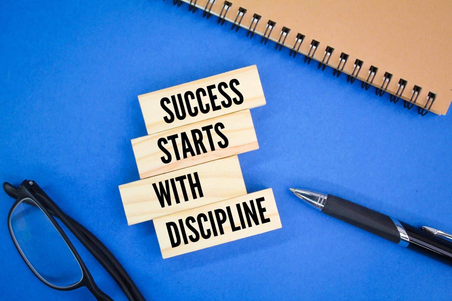 glasses, books and pens with the words Success starts with discipline. motivational quotes
