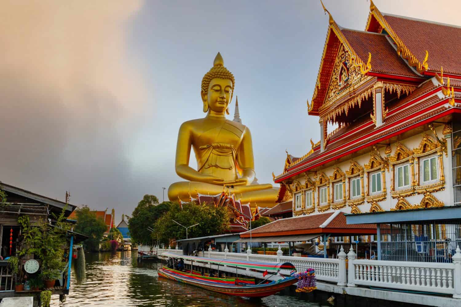 Big Buddha (Wat Paknam) at sunset. Chao Phraya river canal cruise. Tourists traveling by traditional boats. Thailand's most important travel destinations. Bangkok, Thailand