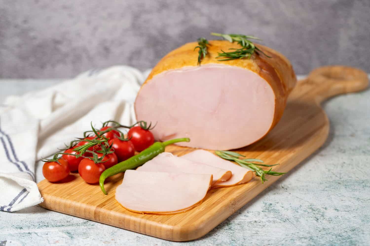 Smoked turkey meat sliced. Smoked turkey-ham fillets on a wood serving board. Deli products.