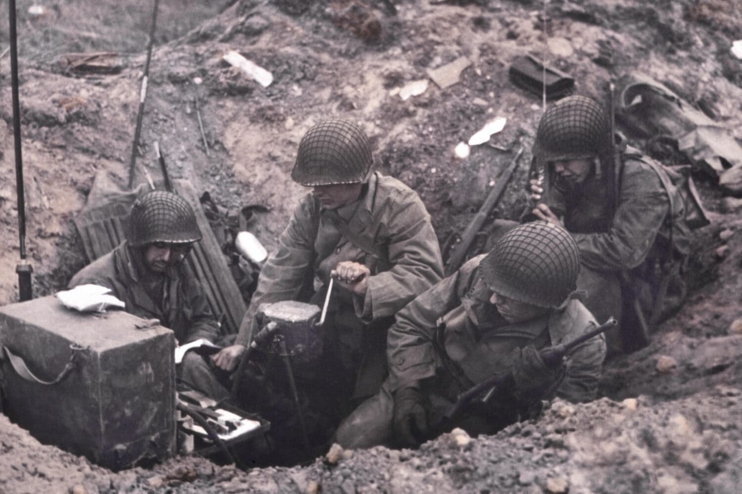 U.S. soldiers of a shore fire control group operating Signal Corps radios. One man cranks the hand generator, while another uses a hand-held radio set. June 6-8, 1944, Normandy, France.
