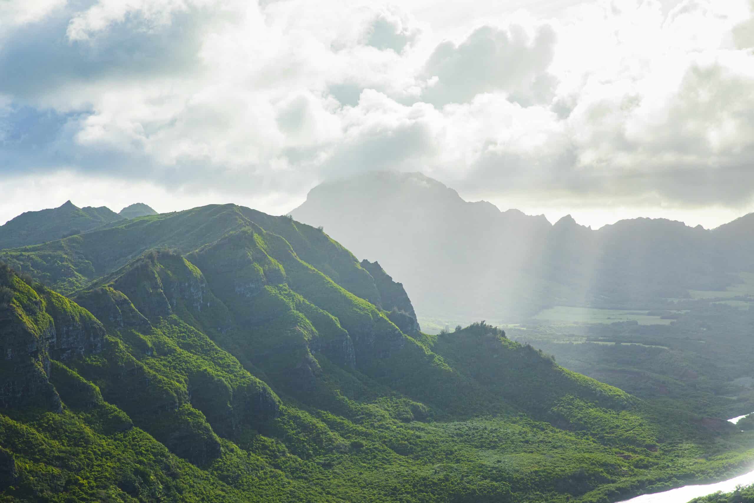 Hawaii forest | Clouds hovering above lush green hawaiian mountain range in golden sunset light