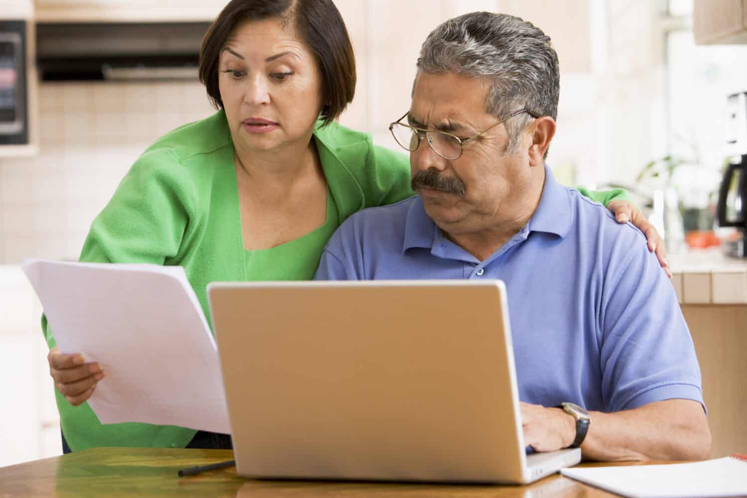 Couple in kitchen working on personal finances, looking worried